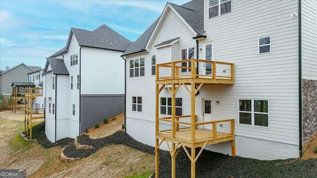 back of house with a wooden deck and a balcony