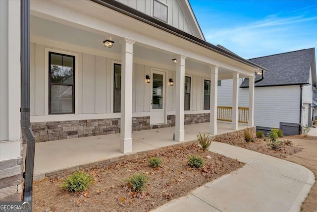 doorway to property with a porch, stone siding, and board and batten siding
