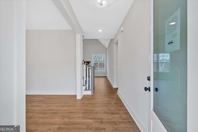 hallway featuring lofted ceiling, baseboards, and wood finished floors