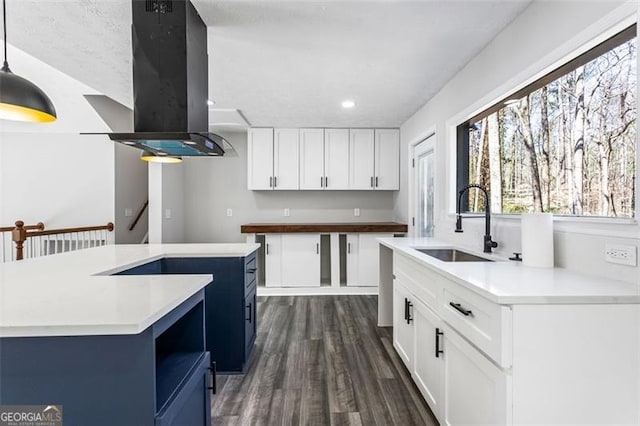 kitchen featuring a kitchen island with sink, a sink, dark wood-style flooring, island exhaust hood, and pendant lighting