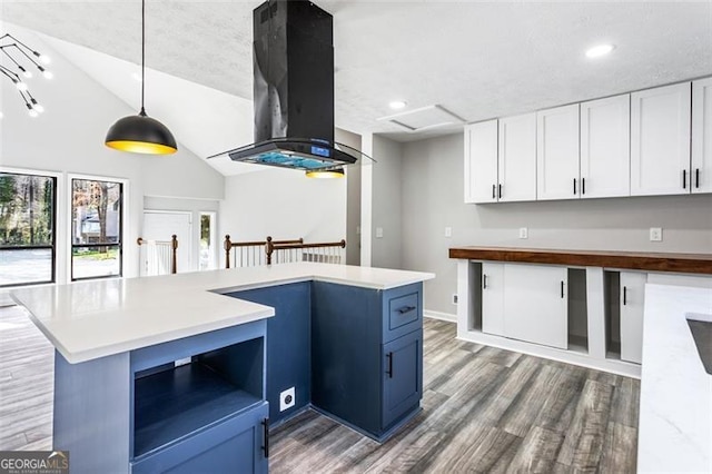 kitchen with island exhaust hood, decorative light fixtures, white cabinetry, vaulted ceiling, and wood finished floors