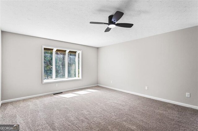 unfurnished room with a textured ceiling, ceiling fan, carpet flooring, and baseboards