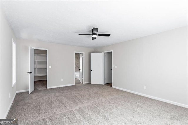 unfurnished bedroom with carpet floors, a closet, ensuite bathroom, baseboards, and a spacious closet