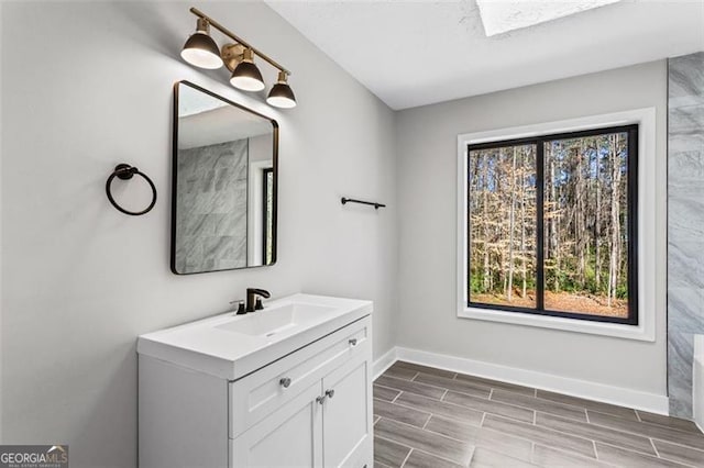 bathroom featuring baseboards, wood finish floors, and vanity