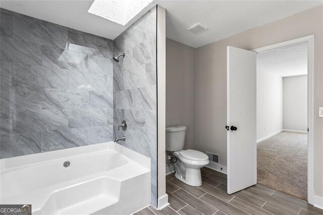 bathroom featuring wood tiled floor, visible vents, baseboards, toilet, and a skylight