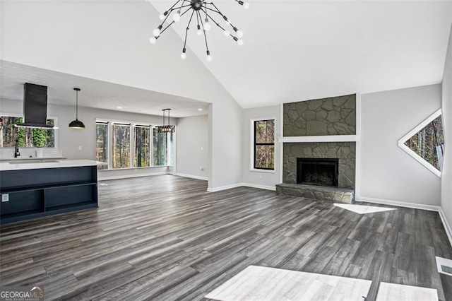 unfurnished living room with high vaulted ceiling, a notable chandelier, dark wood finished floors, and baseboards