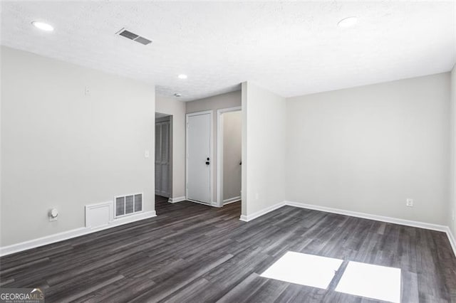 empty room with baseboards, visible vents, and dark wood-type flooring