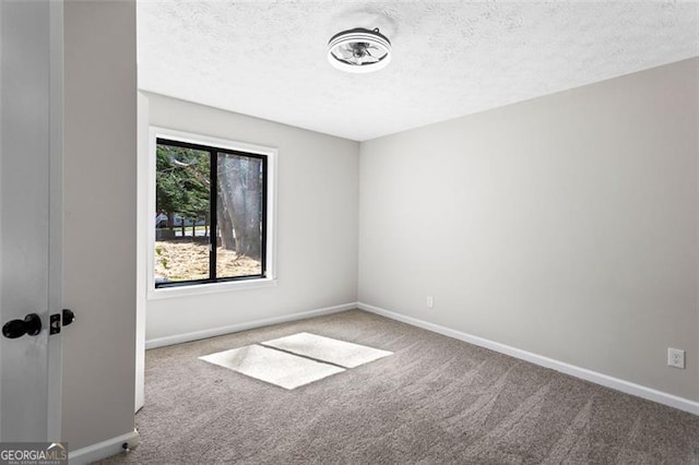 spare room with a textured ceiling, baseboards, and carpet floors
