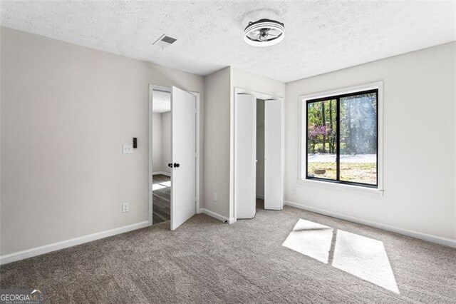 unfurnished bedroom featuring baseboards, visible vents, carpet floors, and a textured ceiling