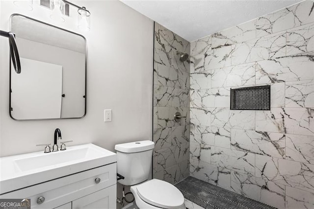 full bathroom featuring tiled shower, toilet, and vanity