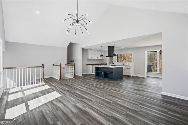 unfurnished living room with high vaulted ceiling, a notable chandelier, dark wood finished floors, and baseboards