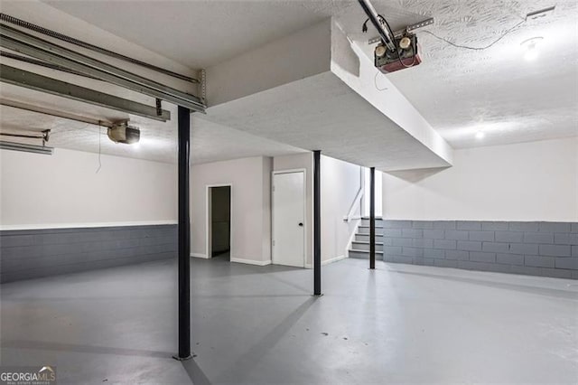 finished below grade area featuring a textured ceiling and stairway