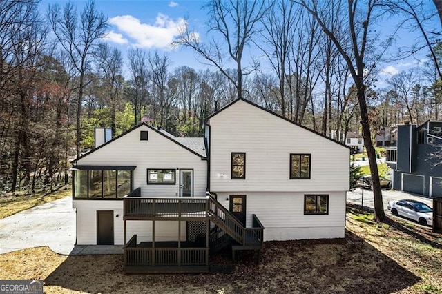 back of property with a deck, stairs, and a sunroom