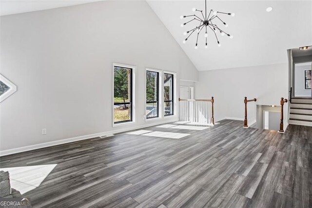 unfurnished living room with stairway, baseboards, an inviting chandelier, dark wood finished floors, and high vaulted ceiling