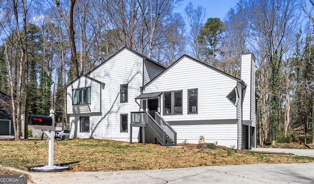 split level home featuring a chimney, a front lawn, concrete driveway, and an attached garage