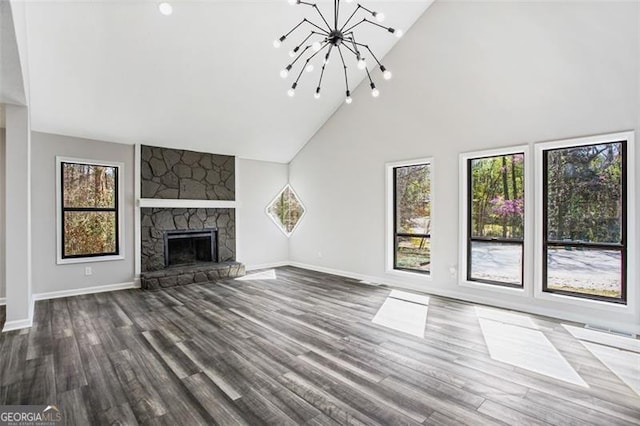 unfurnished living room featuring a chandelier, high vaulted ceiling, a healthy amount of sunlight, and dark wood-type flooring