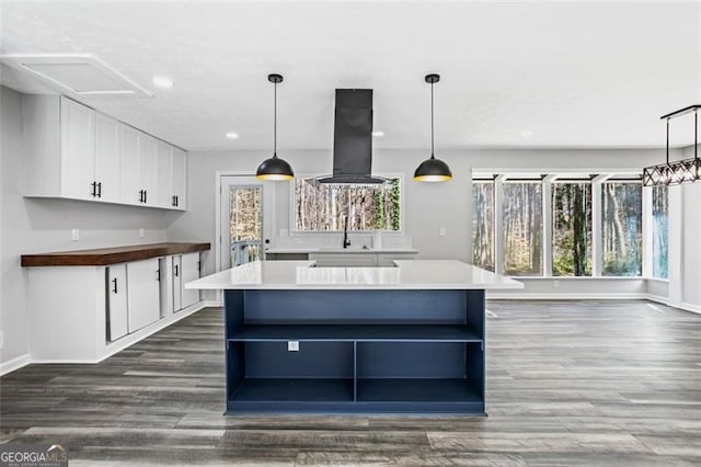 kitchen with white cabinetry, open shelves, a kitchen island, baseboards, and island exhaust hood