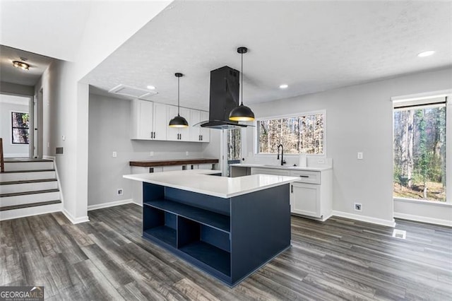 kitchen featuring open shelves, white cabinets, a sink, baseboards, and island exhaust hood