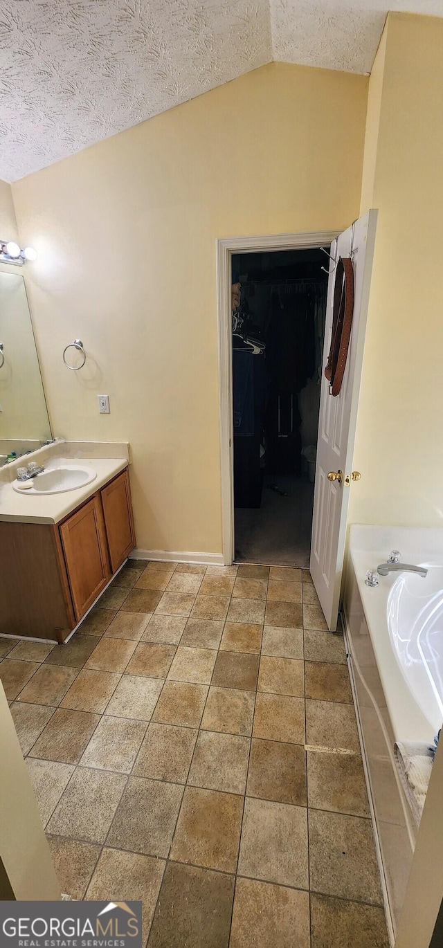 194 Goldleaf Dr, Hampton, GA 30228 - full bath featuring a spacious closet, vanity, lofted ceiling, a bath, and a textured ceiling