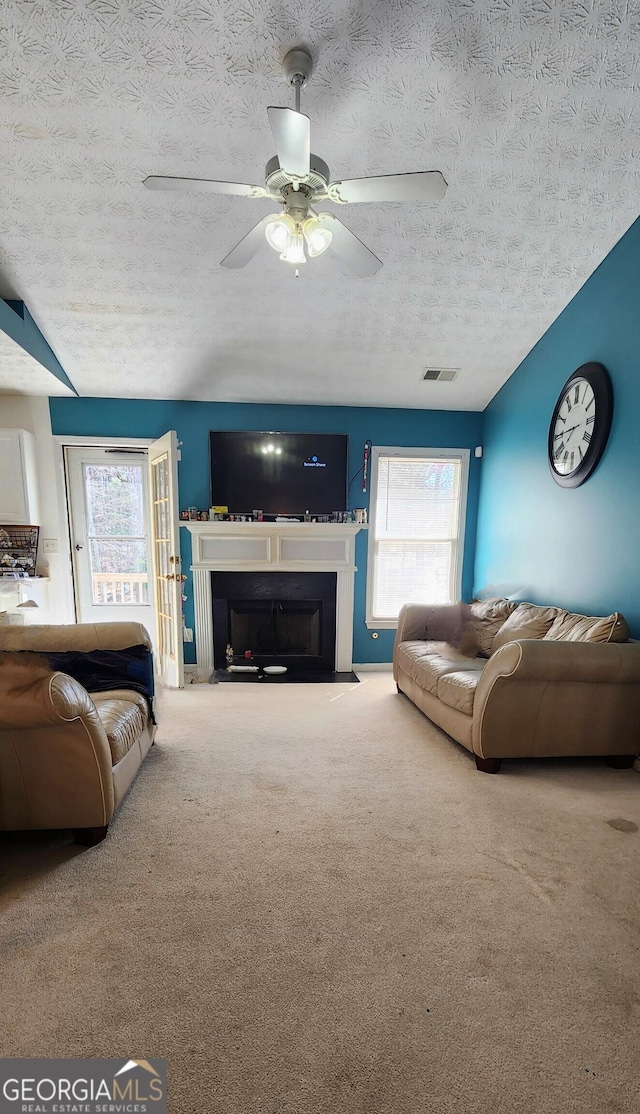194 Goldleaf Dr, Hampton, GA 30228 - carpeted living area featuring visible vents, a fireplace with flush hearth, a textured ceiling, and a ceiling fan