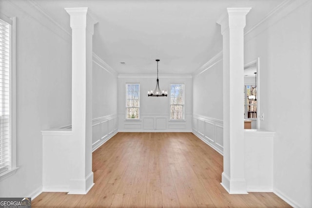 unfurnished dining area featuring a decorative wall, crown molding, an inviting chandelier, and wood finished floors
