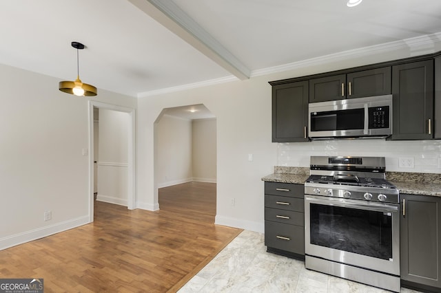 kitchen featuring arched walkways, ornamental molding, stainless steel appliances, baseboards, and backsplash