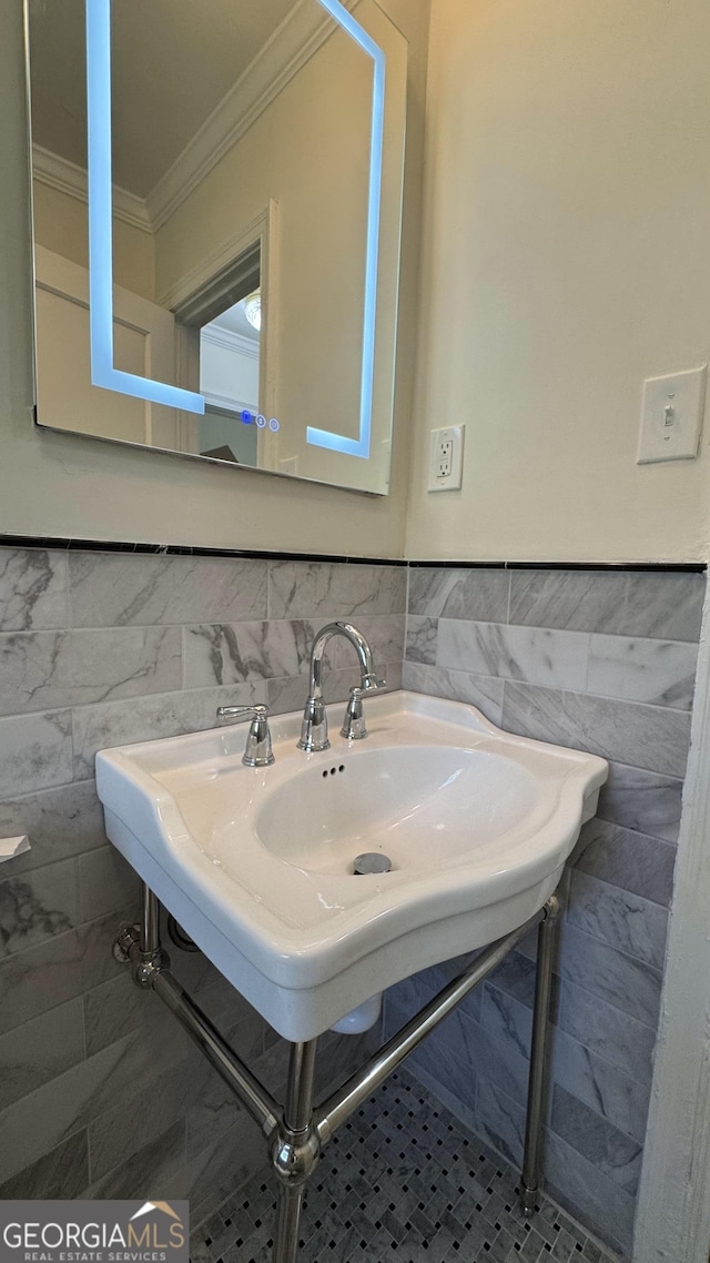 bathroom featuring a sink, tile walls, crown molding, and a wainscoted wall