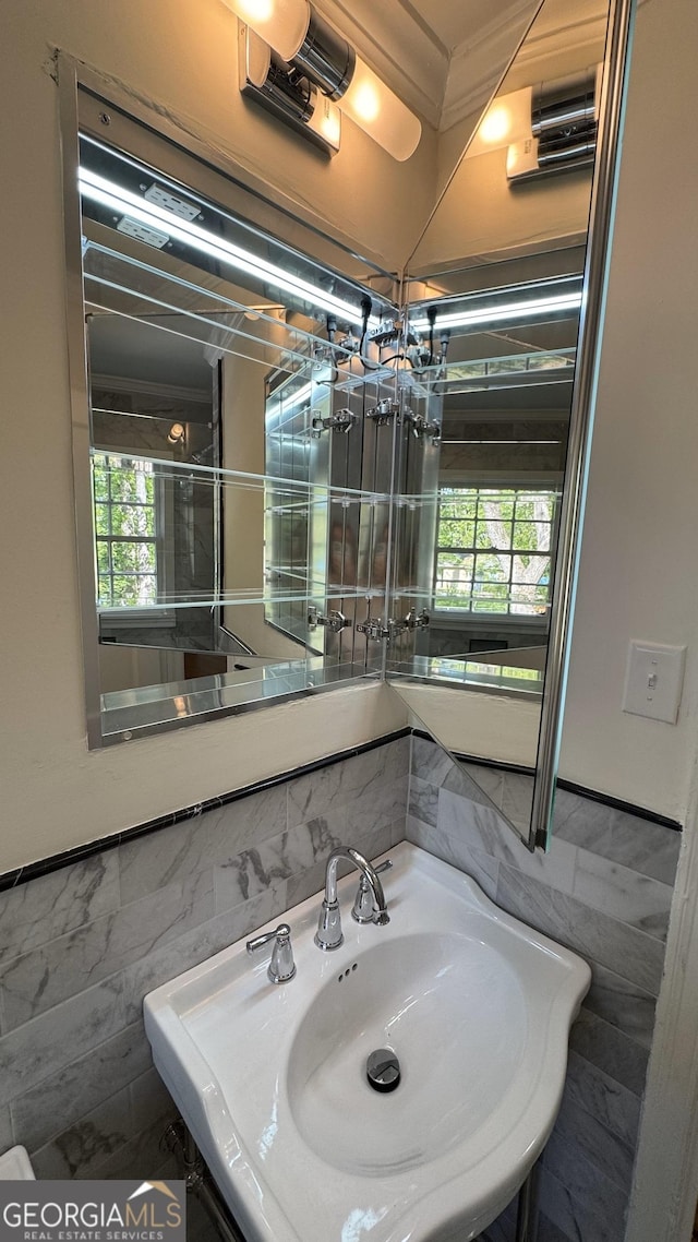 bathroom with a sink, tile walls, and a wainscoted wall