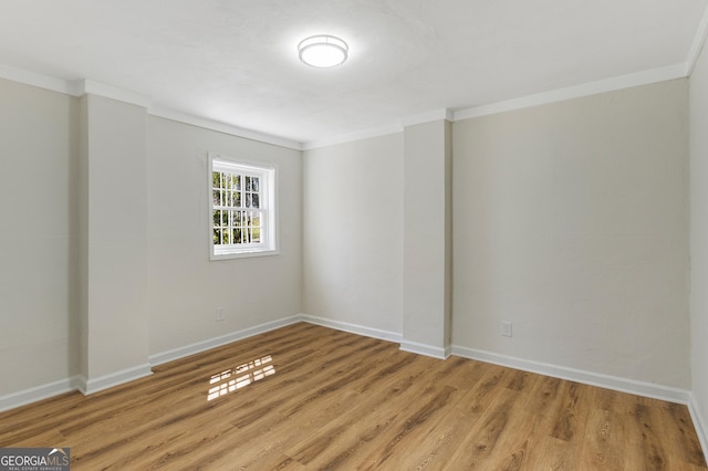 unfurnished room featuring light wood-style flooring, baseboards, and ornamental molding
