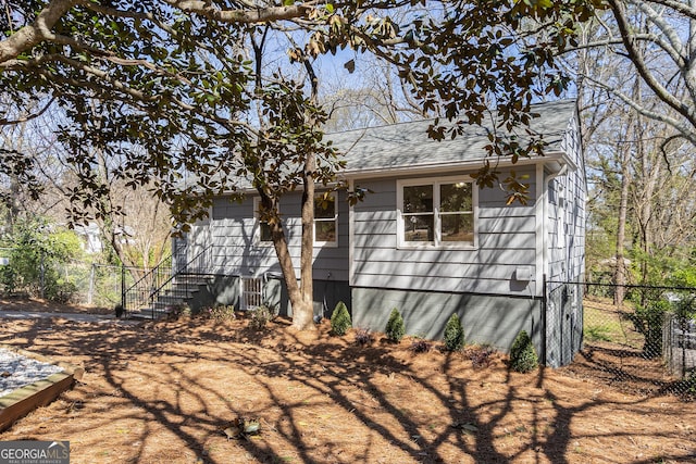 view of side of home with fence and a shingled roof