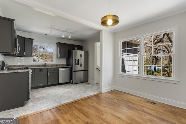 kitchen with stainless steel appliances, visible vents, a sink, and ornamental molding