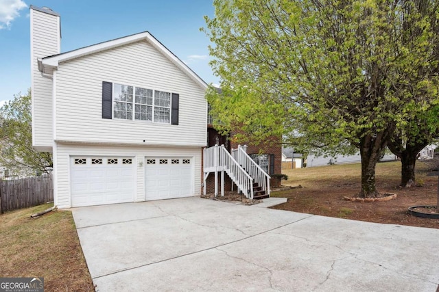 view of front facade with stairway, fence, a chimney, concrete driveway, and a garage