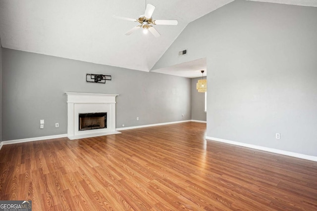 unfurnished living room with wood finished floors, baseboards, visible vents, a fireplace with flush hearth, and ceiling fan
