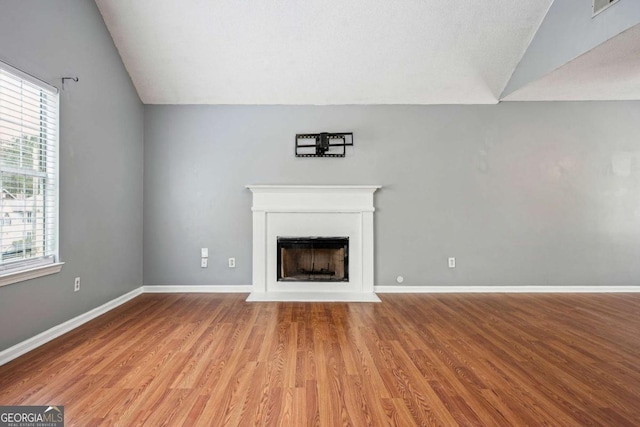 unfurnished living room featuring baseboards, light wood-style floors, a fireplace, and vaulted ceiling