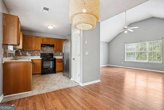 kitchen featuring visible vents, black gas stove, stainless steel fridge, a ceiling fan, and a sink