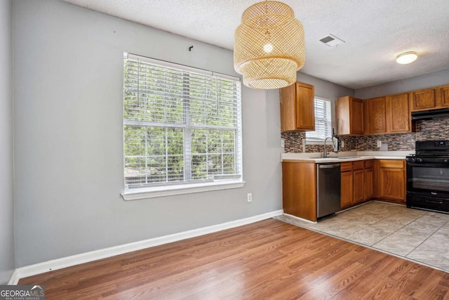 kitchen with under cabinet range hood, a sink, stainless steel dishwasher, gas stove, and light countertops