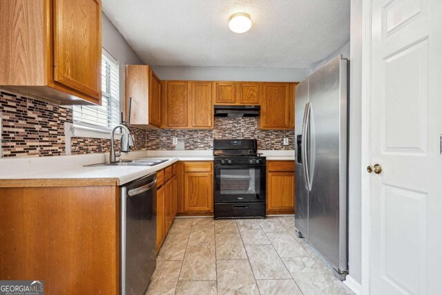 kitchen with brown cabinetry, a sink, stainless steel appliances, light countertops, and under cabinet range hood