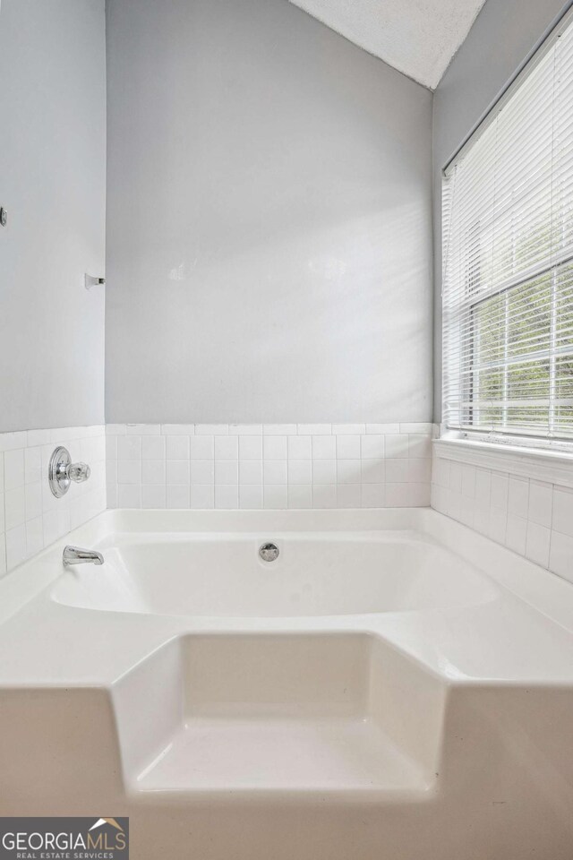 full bathroom with a garden tub and a textured ceiling