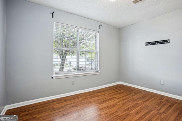 unfurnished room with baseboards, a textured ceiling, and wood finished floors