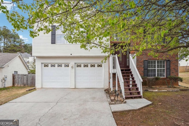 view of front of home with brick siding, fence, stairway, concrete driveway, and a garage