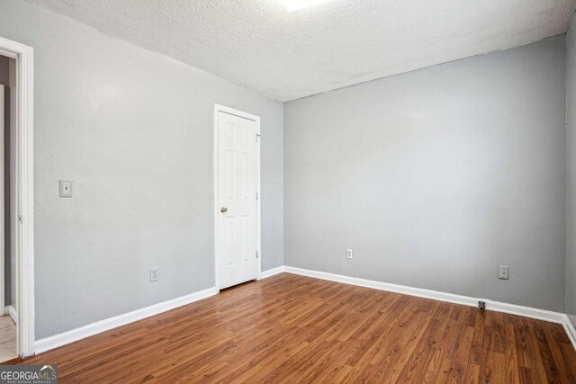 unfurnished room featuring baseboards, a textured ceiling, and wood finished floors