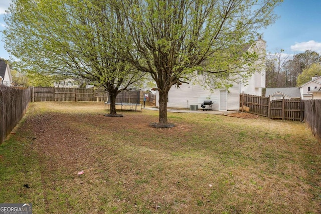 view of yard with a trampoline and a fenced backyard
