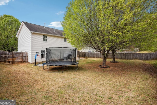 view of yard featuring a trampoline and a fenced backyard