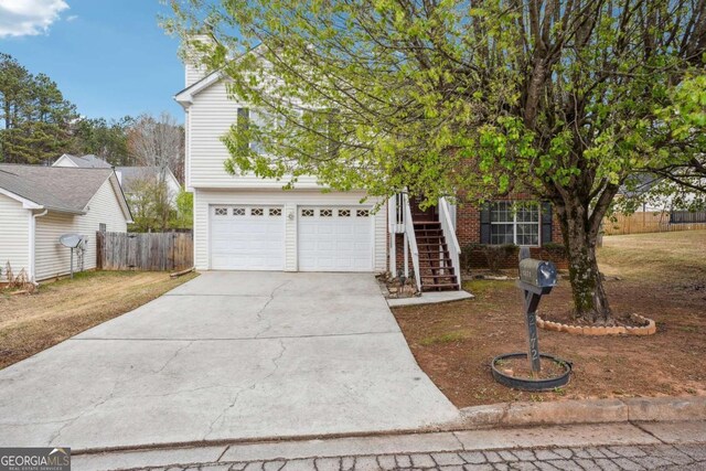 view of front of house featuring concrete driveway, stairway, an attached garage, and fence