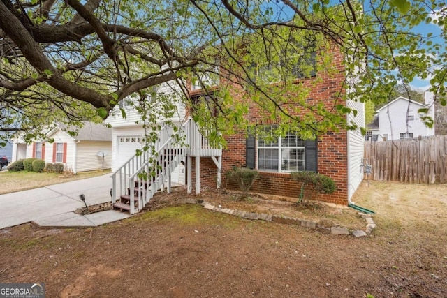 obstructed view of property with brick siding, an attached garage, concrete driveway, and fence