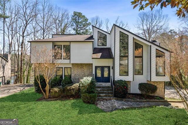 view of front facade with a front yard, french doors, and stone siding
