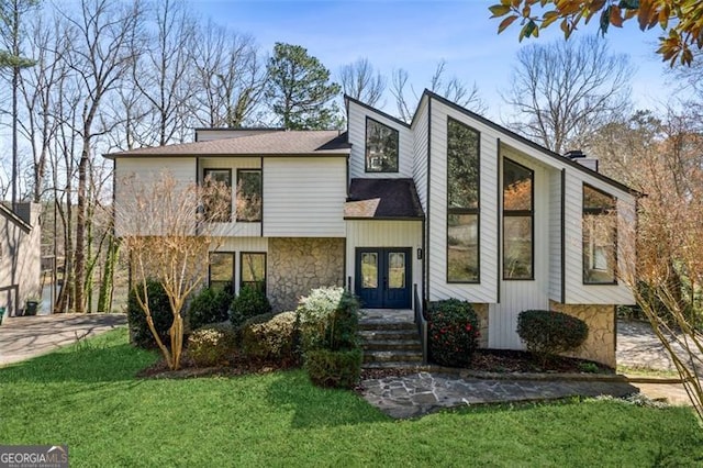 view of front of house featuring stone siding, french doors, and a front yard