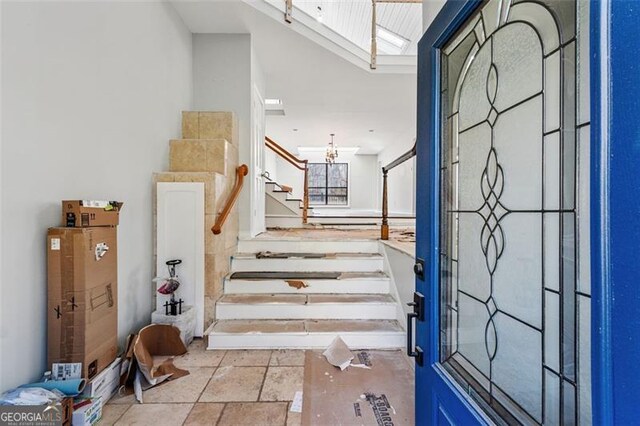 entrance foyer with stone tile floors, stairway, and an inviting chandelier