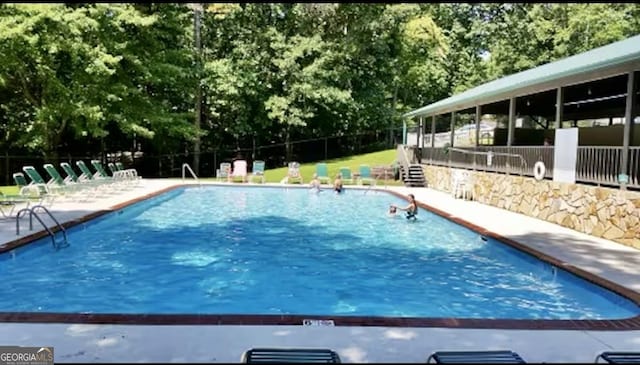 community pool with a patio and fence