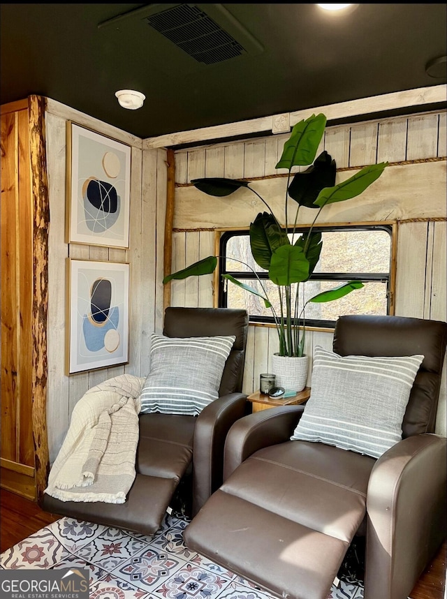 living area featuring wooden walls, visible vents, and wood finished floors